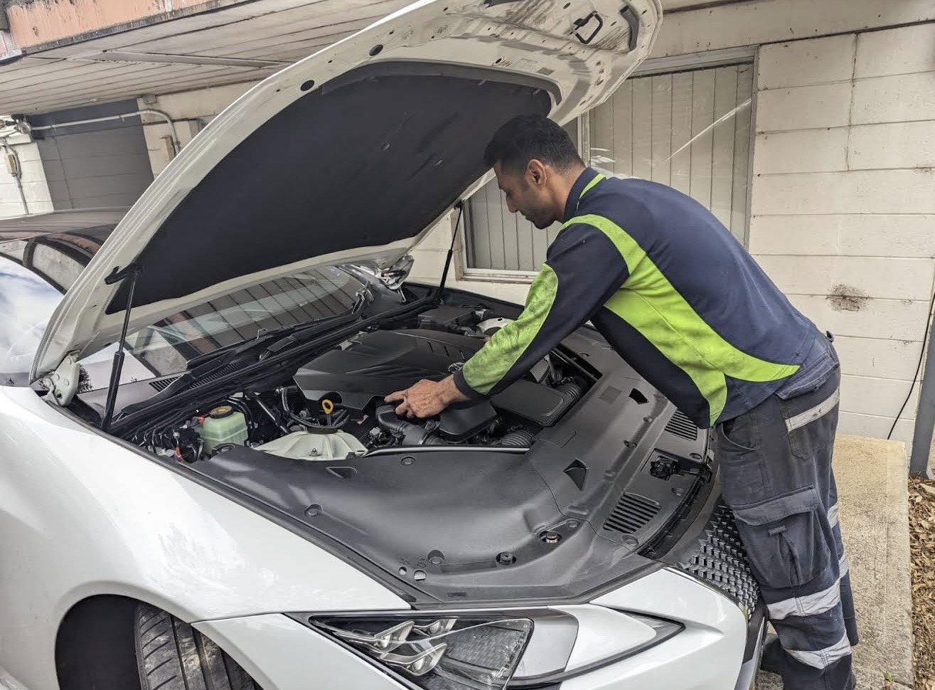Mehdi inspecting an engine bay in a Northmead driveway